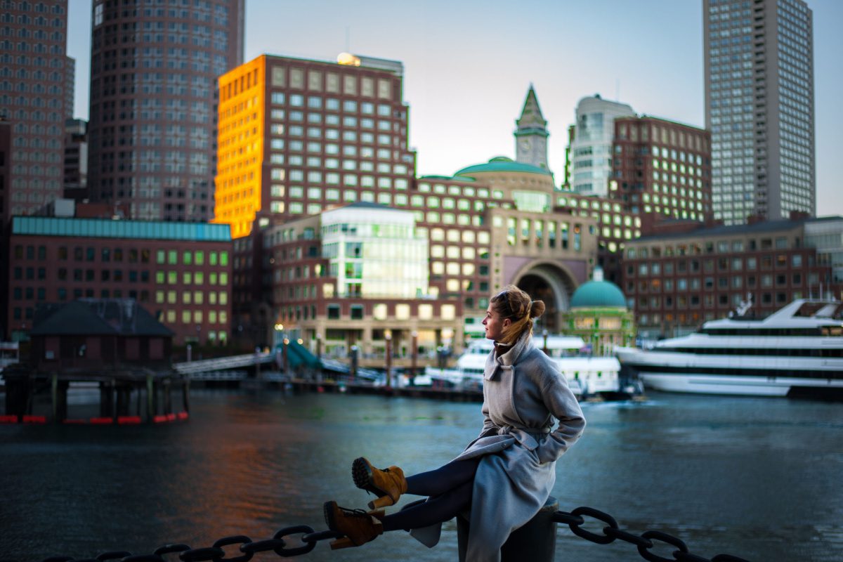 Woman sitting by the harbor, contemplating her renting prospects in Boston on a $100,000 salary