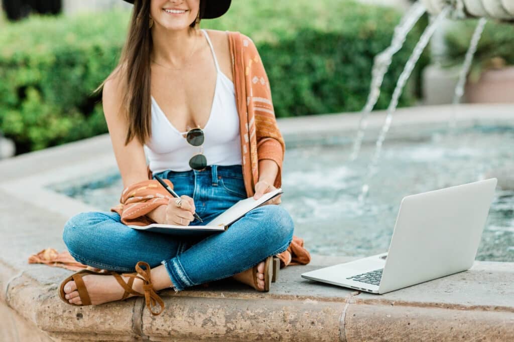 person sitting next to water fountain with laptop. Online Jobs For Teenagers.