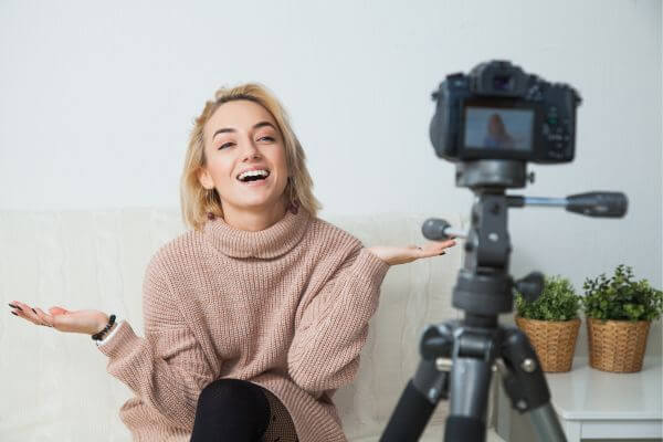 Picture of a girl smiling while filming using her camera and stand.