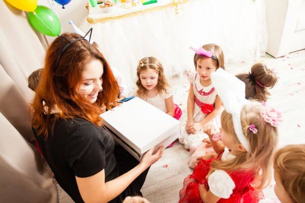 Image of the girl entertaining the kids in their party with a balloon and party props.