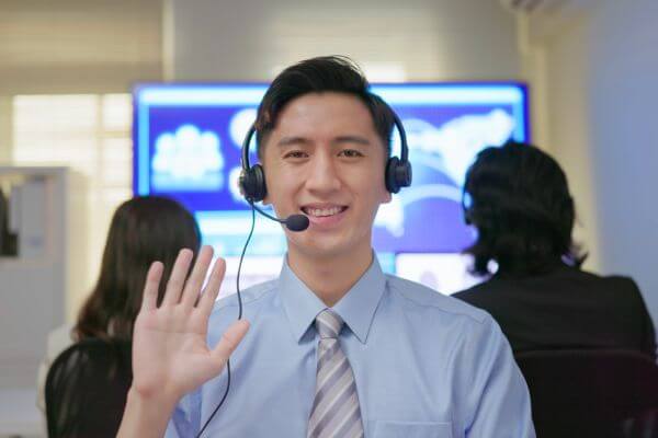 The image of a man wearing a head phone with a microphone and waving.