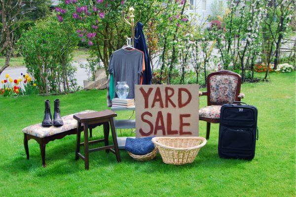 The picture of house stuff putting together in a ground with a signage of yard sale.