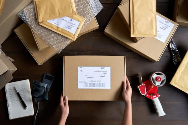 Image of the  boxes and brown envelope  with a notebook, cutter, and tape.