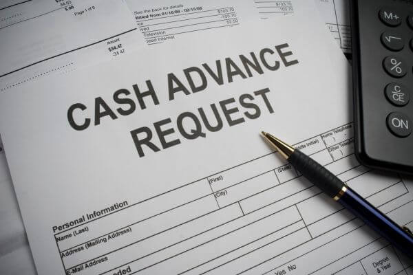 Image of a cash advance request form with a pen and calculator.