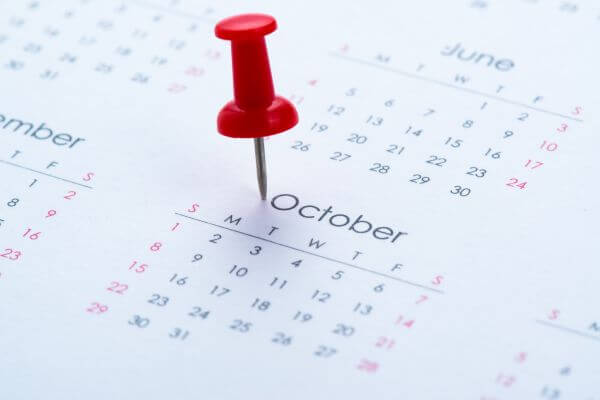 Image of a white calendar with a red pinned in October.