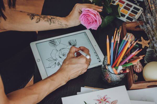 Image of a digital artist working on a sketching a pink rose as  a subject of the art.